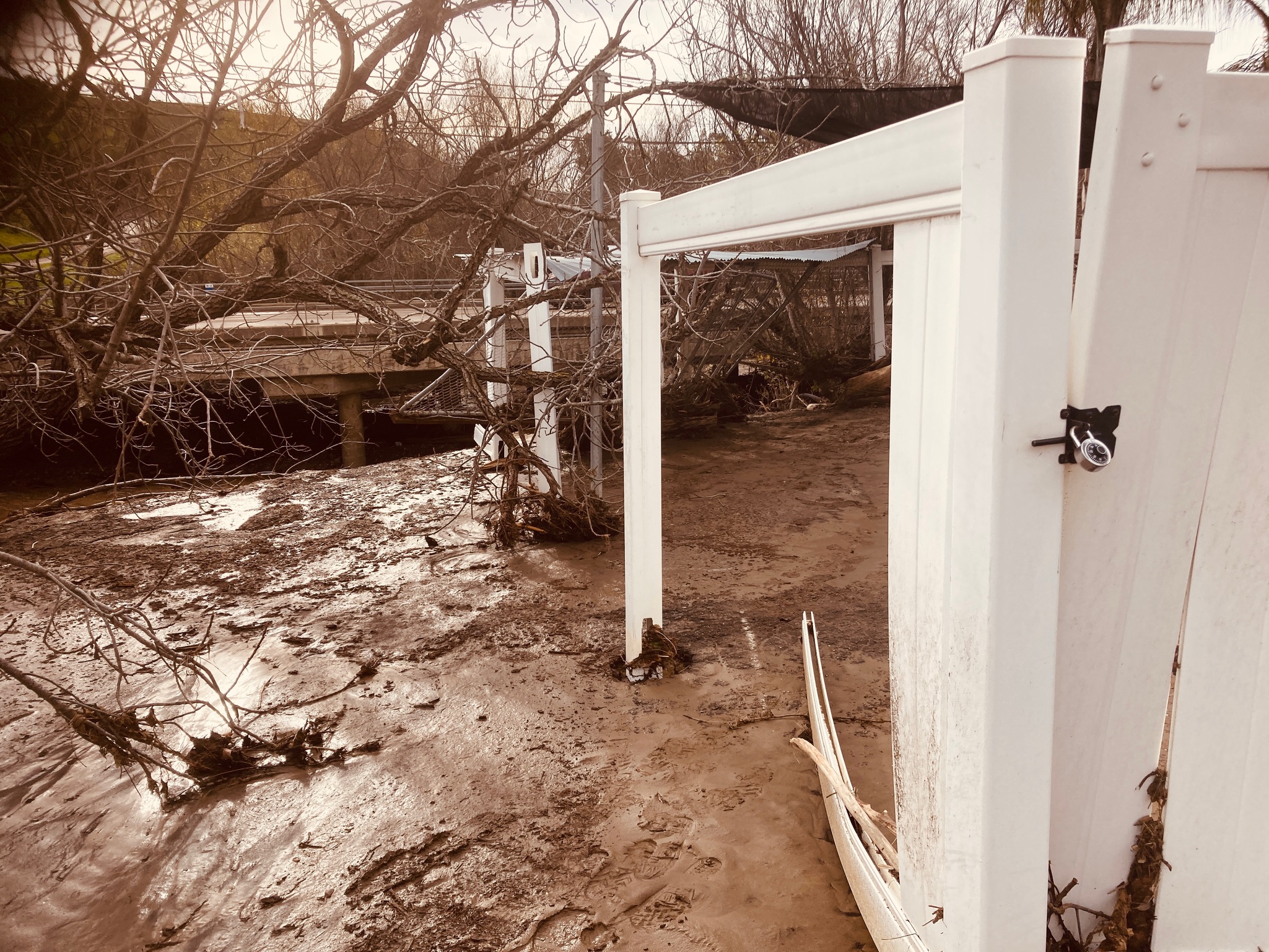 A white fence partially submerged in muddy water
