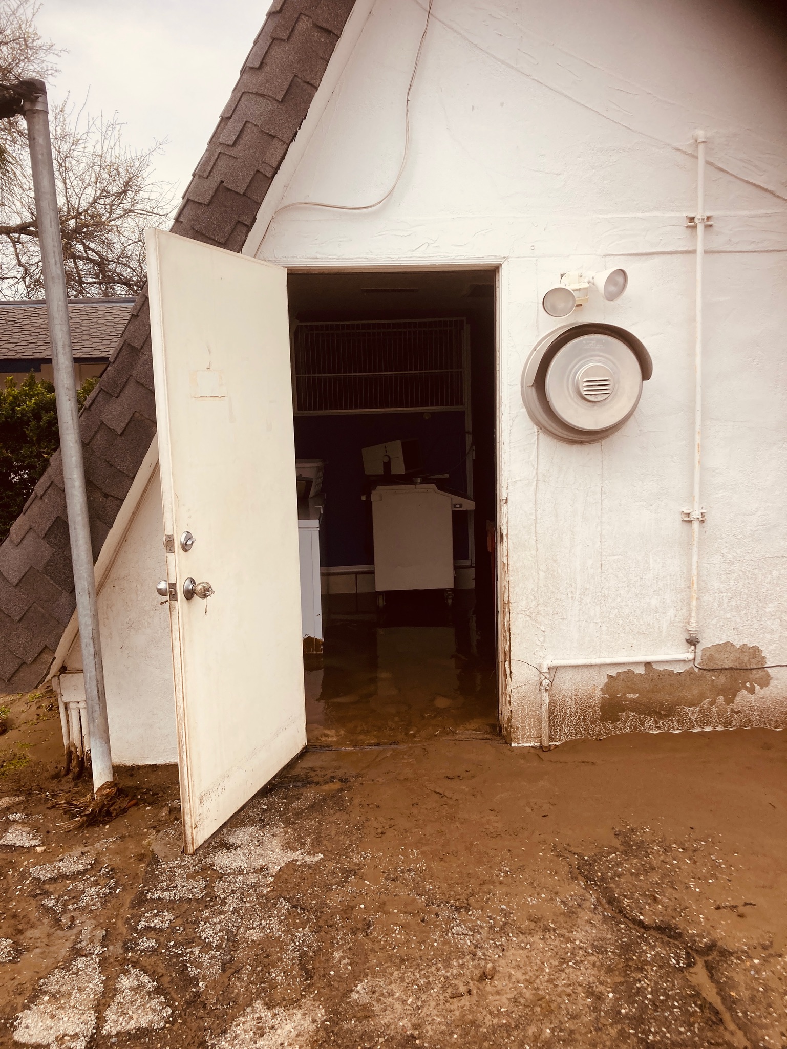 A door to a small building partially submerged in floodwaters