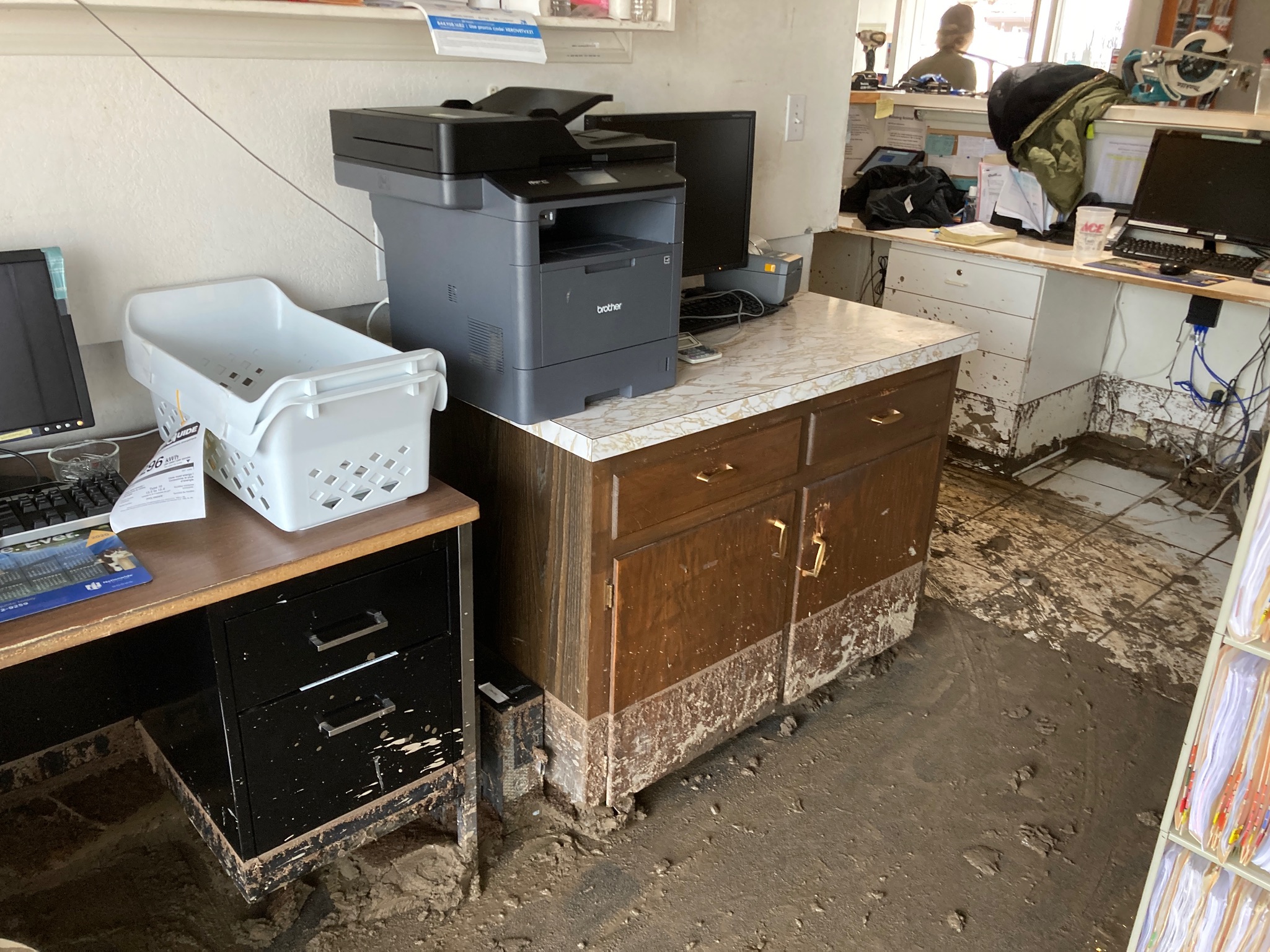 A cluttered office space featuring a disorganized desk and a printer