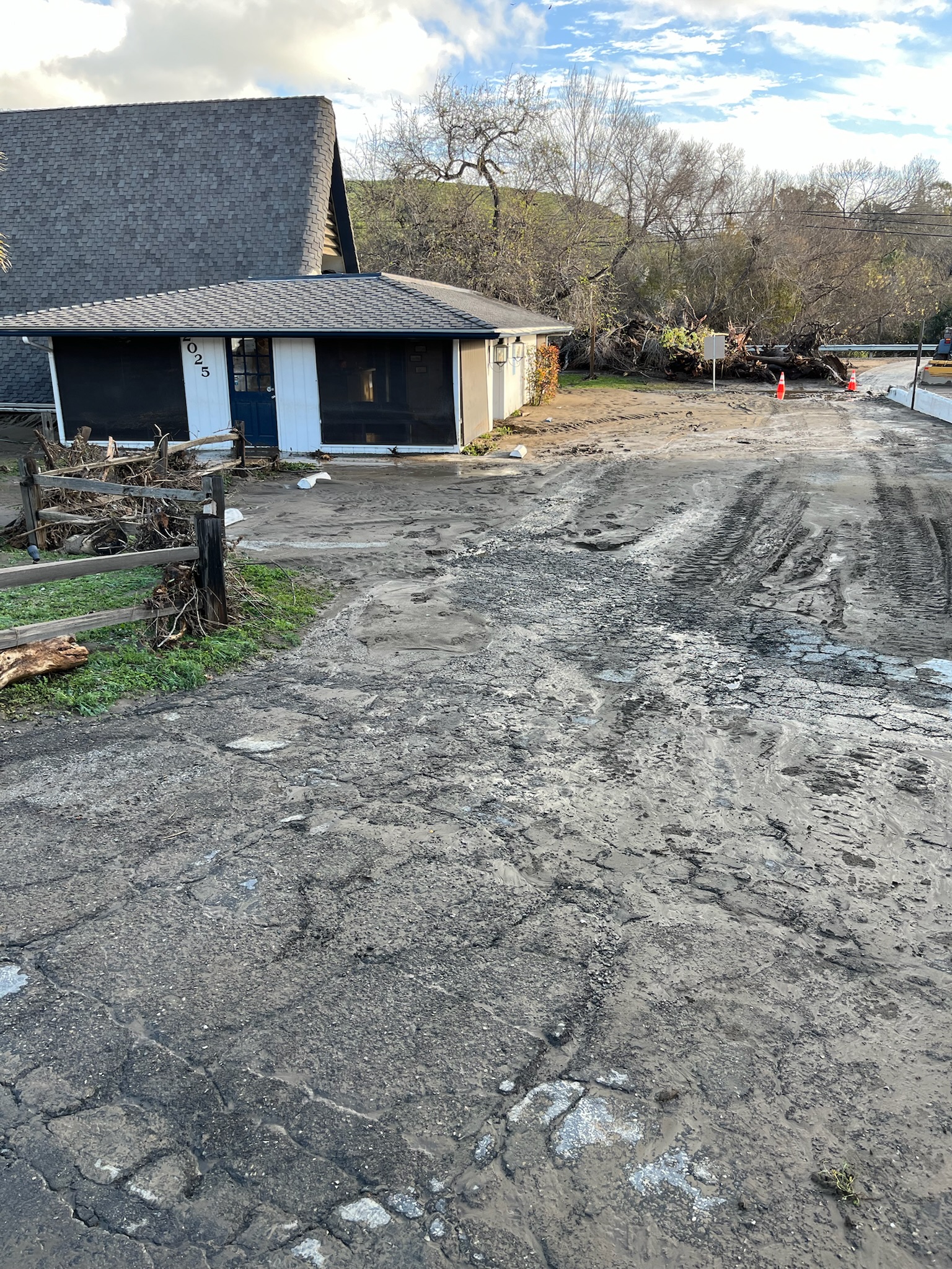 A dirt road leading towards a house set against a natural background