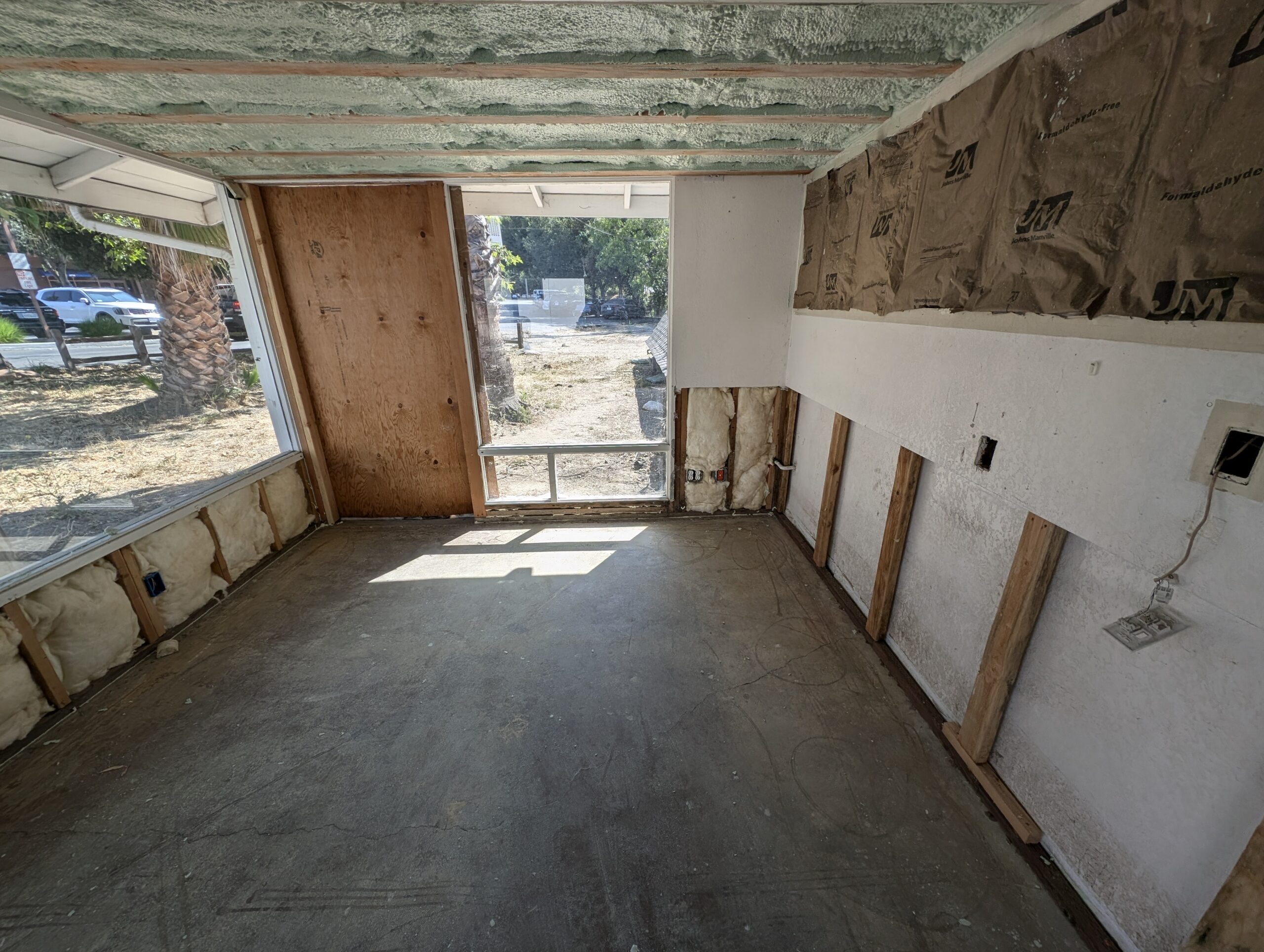 A room featuring a window and a wall entirely covered in drywall