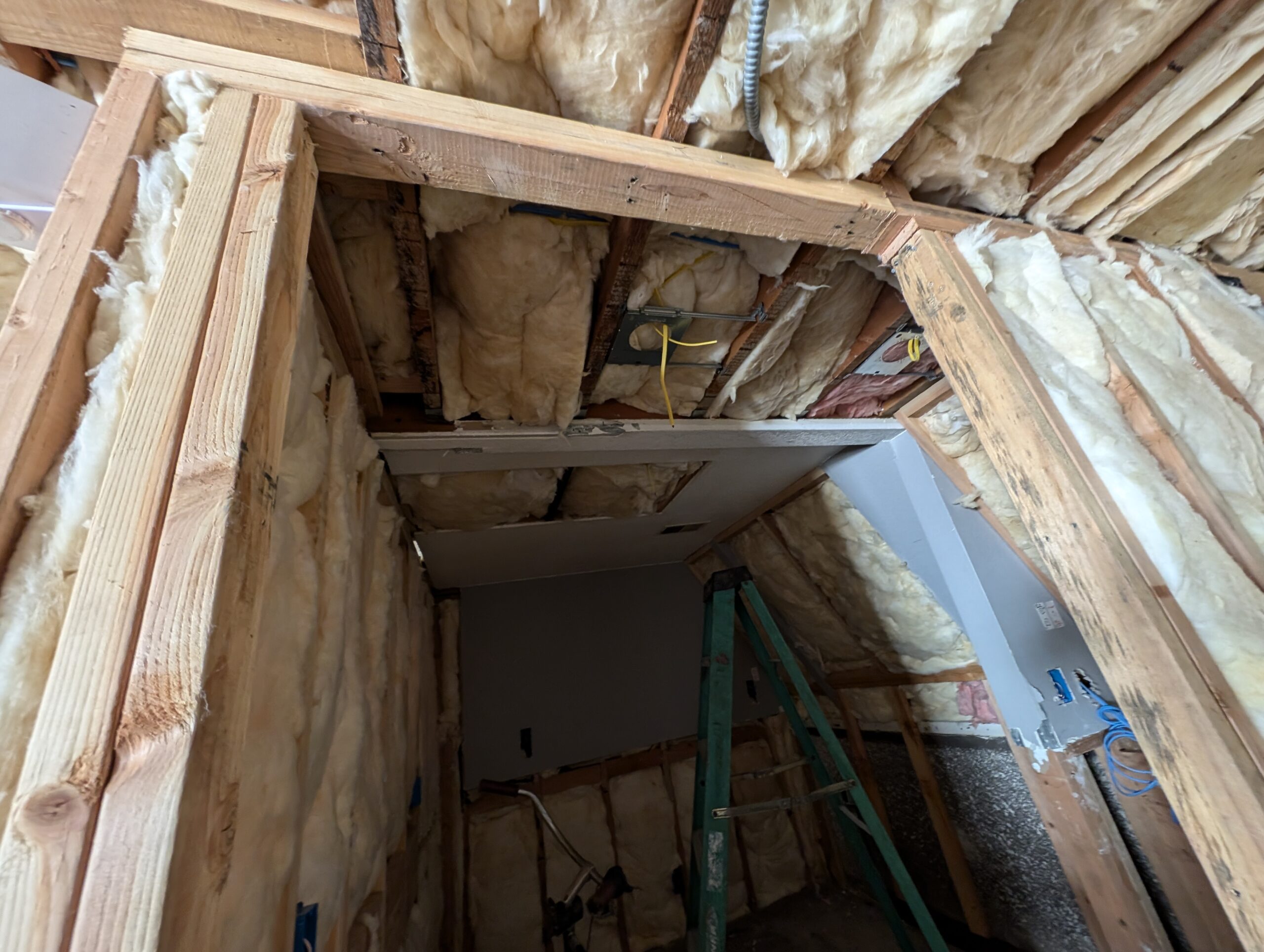 A bathroom featuring exposed insulation and wooden framing