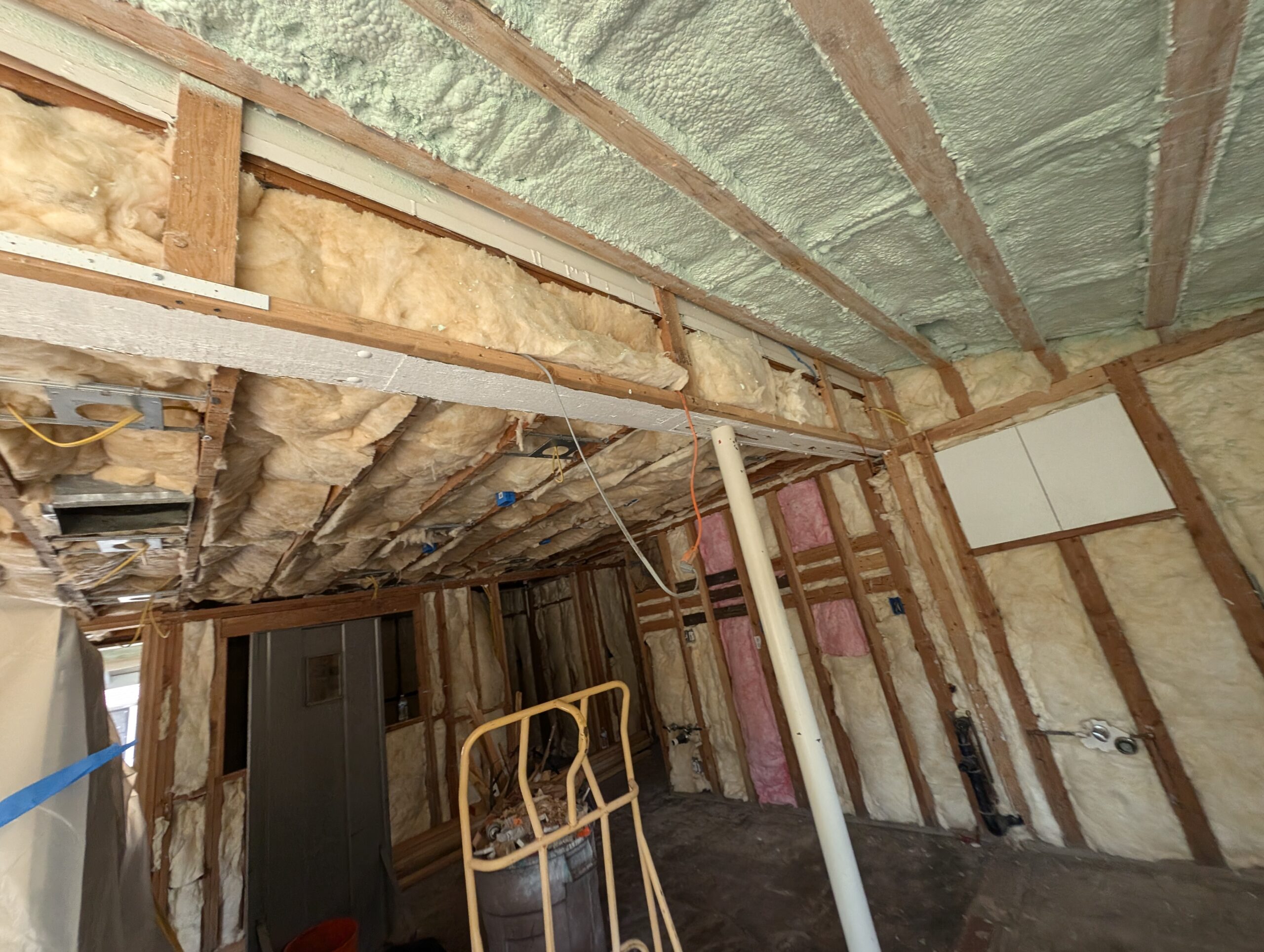 A room featuring exposed wood framing and insulation